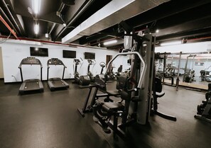 A gym with treadmills, weight machines, and a mirrored wall. - Oceanfront Terrace Apartment - Steps to Beach (Carolina)