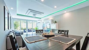 A modern dining area with a dark wooden table, cushioned chairs, and a central decorative piece. - Oceanfront Terrace Apartment - Steps to Beach (Carolina)
