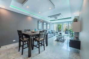 A modern dining area with a dark wooden table and chairs, a sofa, and a small coffee table. - Oceanfront Terrace Apartment - Steps to Beach (Carolina)