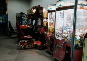 Eine Reihe von Spielautomaten, darunter ein Rennspiel und ein Krabspielsautomat mit Plüschtieren.