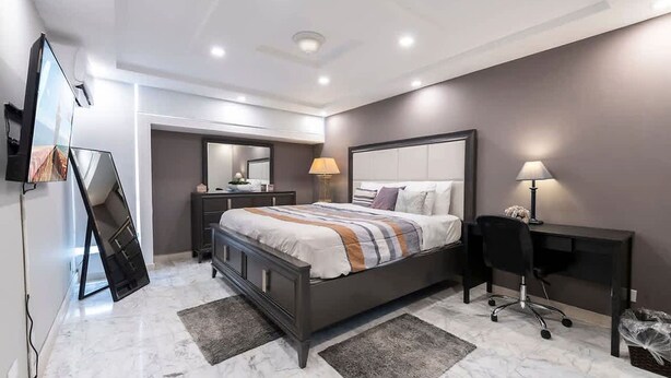 A modern bedroom with a bed, bedside tables, a desk, and a chair. - Oceanfront Terrace Apartment - Steps to Beach (Carolina)