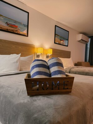 Ein Hotelzimmer mit einem Bett, zwei gestreiften Kissen, einem Holz-Kopfstück und zwei Wandlampen. An der Wand befinden sich gerahmte Bilder.