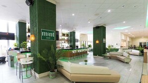 Eine moderne Hotelhalle mit Barbereich, Sitzgelegenheiten und einer Rezeption.