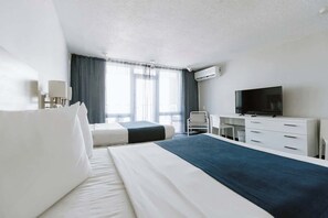 A hotel room with a bed, a desk, a chair, a television, and an air conditioning unit. - Clean Beach Studio with Balcony in Isla Verde (Carolina)