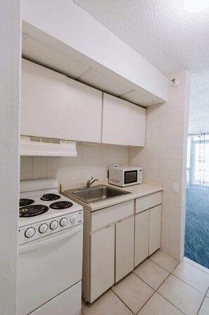 A compact kitchen with a stove, sink, and microwave. - Clean Beach Studio with Balcony in Isla Verde (Carolina)