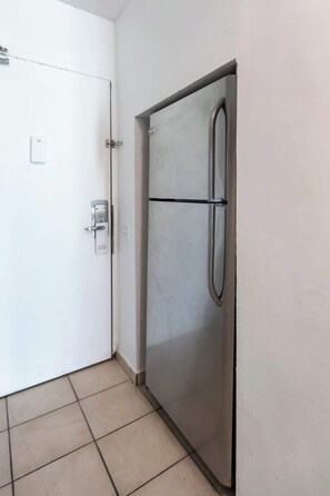 A room with a white door, a stainless steel refrigerator, and tiled flooring. - Clean Beach Studio with Balcony in Isla Verde (Carolina)