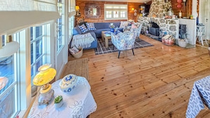 L’intérieur chaleureux d’un chalet avec une cheminée en pierre, un plancher en bois, un canapé bleu et un coin repas.
