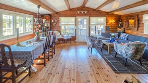 L’intérieur d’un chalet en bois comprend un coin repas, un canapé et une cheminée.
