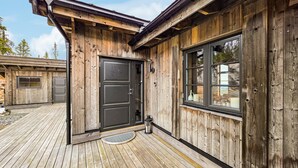 Une cabane en bois avec une grande porte, une fenêtre et une terrasse.