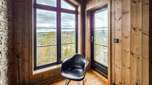 Une pièce dotée de grandes fenêtres, d’une chaise noire et de murs en bois.