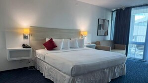 Une chambre d’hôtel avec un grand lit, des lampes de chevet, un téléphone, une chaise et une vue sur l’extérieur.