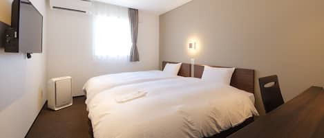 A hotel room with two beds, a TV, an air conditioner, a window with curtains, and a bedside table.