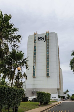 A tall white building with the letters 'esj' on the facade, surrounded by palm trees and a street. - Oceanfront Studio w/ Beach Access & Parking (Carolina)