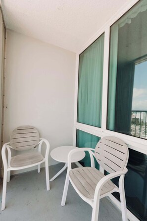 A balcony with two white plastic chairs and a small round table. - Oceanview Studio w/Balcony • Ocean Breezes + A/C (Carolina)
