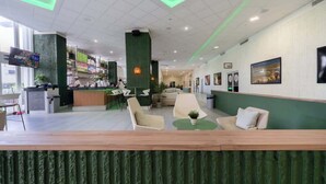 Een moderne hotel lobby met een receptiebalie, een zithoek en kunstwerken aan de wanden.
