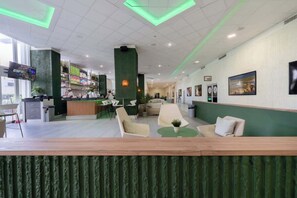 Eine moderne Hotelhalle mit Empfangstresen, Sitzgelegenheiten und Kunstwerken an den Wänden.