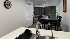 Una cocina moderna con un lavamanos, una mesa de comedor y un sofá al fondo.