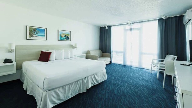 Habitación de hotel con una cama grande, un escritorio, una silla, un sofá y dos cuadros en la pared.