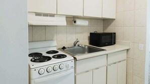 Una cocina funcional con estufa, lavamanos y microondas.
