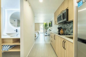 Eine moderne Küche mit Holzschränken, einem Edelstahlkühlschrank und einer Mikrowelle.