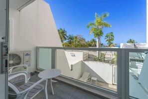 Ein Balkon mit Glasgeländer, einem kleinen Tisch und zwei Stühlen.