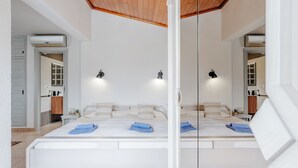 A large bed with a wooden ceiling, white walls, and two bedside lamps.