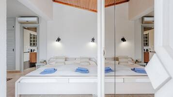 A large bed with a wooden ceiling, white walls, and two bedside lamps.