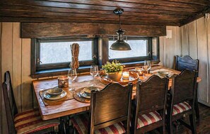 Una mesa de comedor de madera con sillas, una lámpara colgante y un ventanal con vistas.
