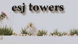 Eine weiße Wand mit dem Schriftzug 'esj towers' in schwarzen Lettern.