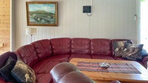 Un divano in pelle rossa con un tavolino in legno, un quadro raffigurante un ponte e una lampada a parete.