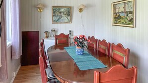 Una sala da pranzo con un tavolo di legno, cuscini a quadri e un vaso di fiori.