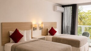 Een hotelkamer met twee bedden, een balkon met een stoel en een airconditioning.