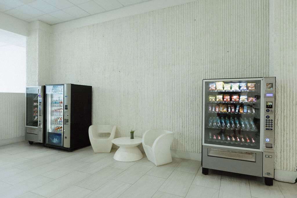 Une chambre propre et moderne, dotée d’un coin salon, de deux distributeurs automatiques et d’un mur à motifs.