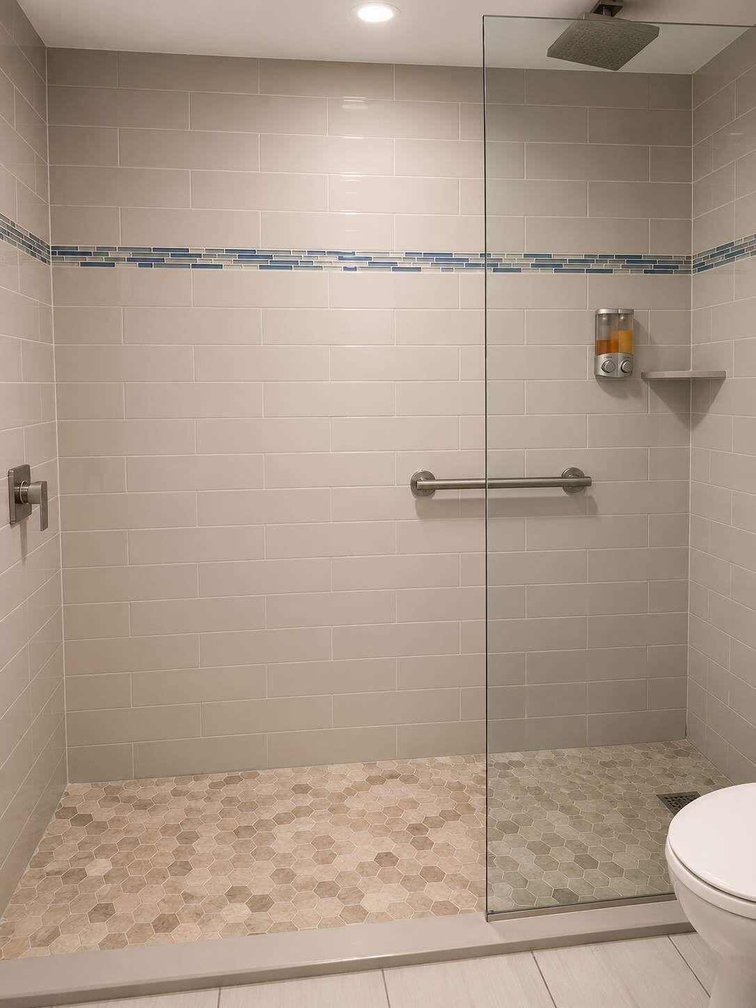 A shower with a glass door, a handrail, and a tiled floor.