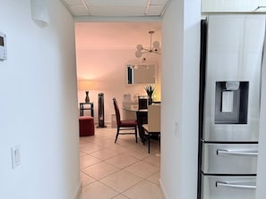 Eine Küche mit einem Kühlschrank, einem Esstisch mit Stühlen und einer Lampe.