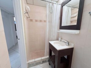 Ein Badezimmer mit Dusche, Waschbecken und Spiegel.