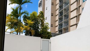 A rooftop patio with white plastic chairs and a table, surrounded by a white wall and a building with balconies. - Beachfront Isla Verde Studio withPrivate Balcony (Carolina)