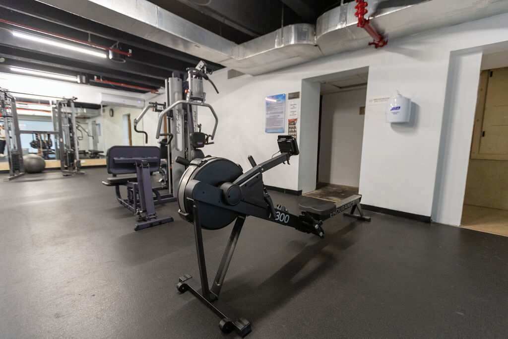 A gym with exercise equipment, a bench, and a wall-mounted sign.