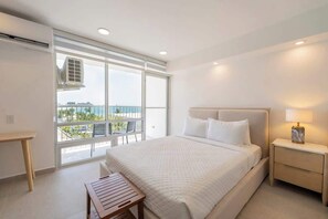 Ein modernes Schlafzimmer mit einem großen Bett, Nachttisch und Blick ins Freie durch ein großes Fenster.