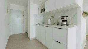 A modern kitchen with white cabinetry, a built-in microwave, a coffee maker, and a sink. - Elegant Studio with Ocean Views - Isla Verde Beach (Carolina)
