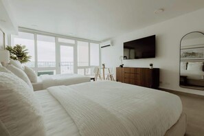 Ein modernes Schlafzimmer mit einem großen Bett, einem Flachbildfernseher, einem Spiegel und einem Balkon mit Blick.