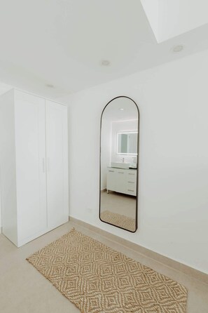 Ein Zimmer mit Schrank, Spiegel und einem gemusterten Teppich.