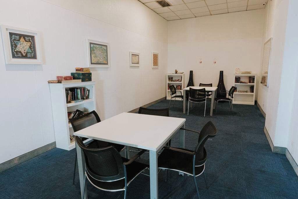 Een vergaderruimte met een witte tafel en stoelen, boekenkasten en ingelijste foto's aan de muren.
