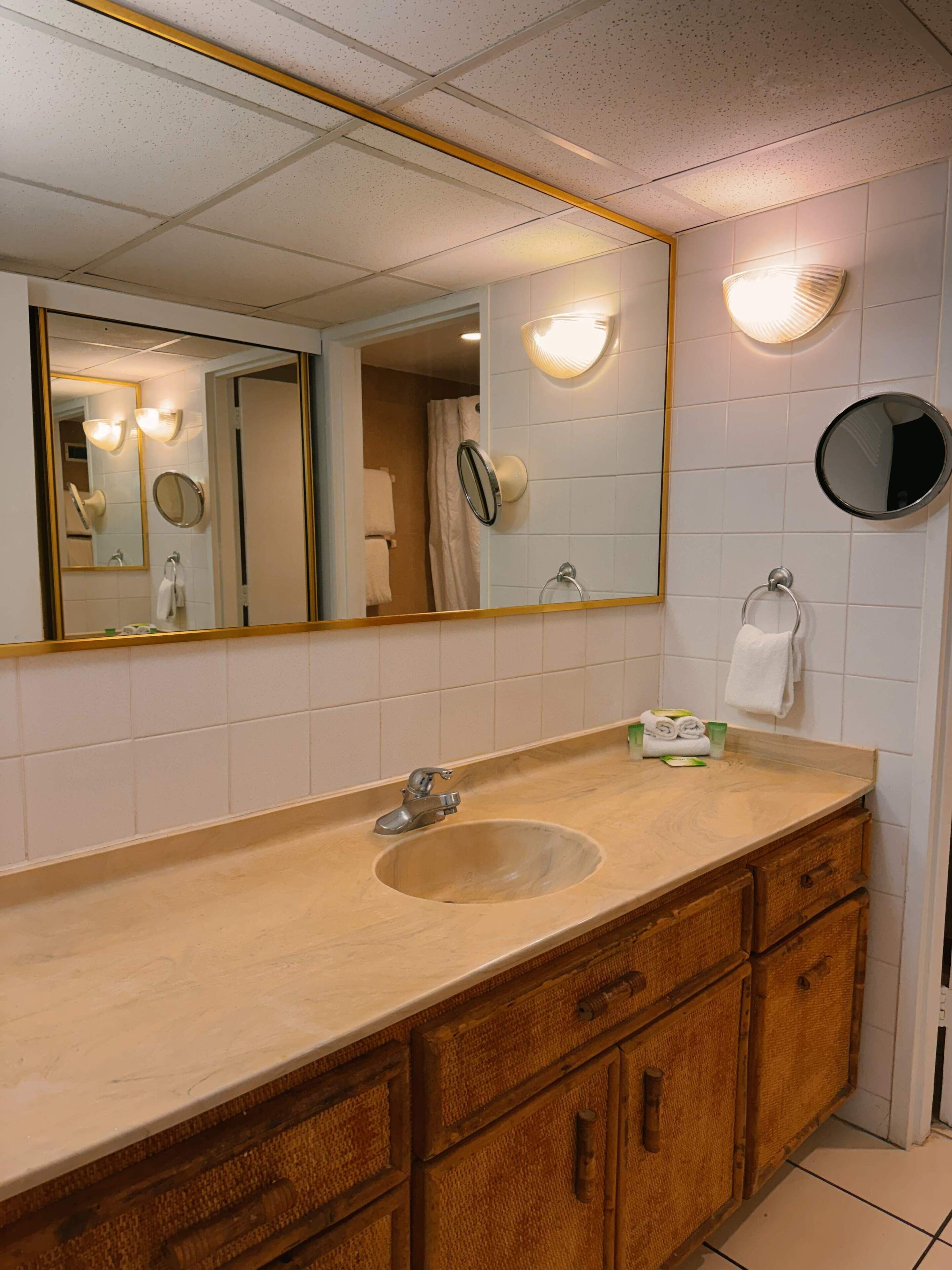 Une salle de bain équipée d’un lavabo, d’un miroir, d’un porte-serviettes et d’un rideau de douche.