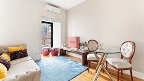 Ein modernes Wohnzimmer mit einer Couch, Hocker, einem Glastisch und Sesseln.