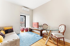 A modern living room with a sofa, ottomans, a glass table, and chairs. - GuestReady - Studio in the heart of Porto (Porto)