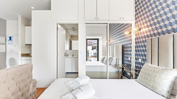 Ein modernes Hotelzimmer mit Bett, Sitzecke und Blick auf die Stadt, inklusive Wand mit Muster.