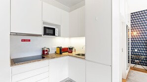 Eine kleine Küche mit weißen Schränken, einer Mikrowelle, einem Wasserkocher und einem Toaster.