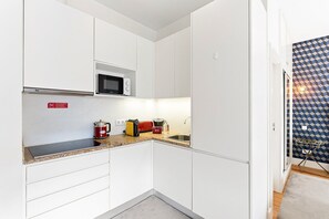 A compact kitchen with white cabinets, a microwave, a kettle, and a toaster. - GuestReady - Studio in the heart of Porto (Porto)