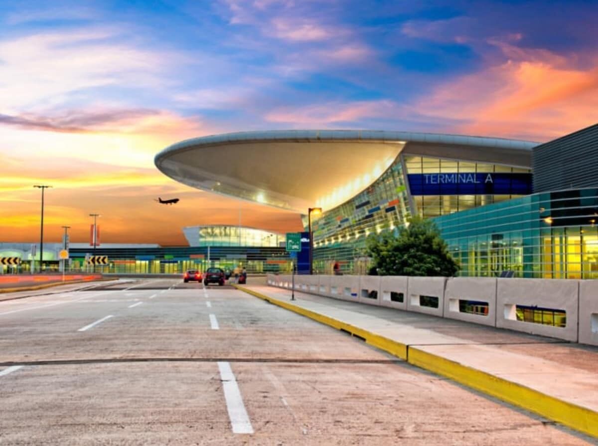 Una terminal aeroportuaria moderna con techo curvo, fachada de vidrio y cielo despejado.